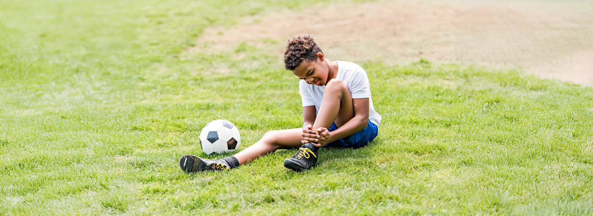 Injured boy holding ankle hurt at soccer practice in Syracuse, NY