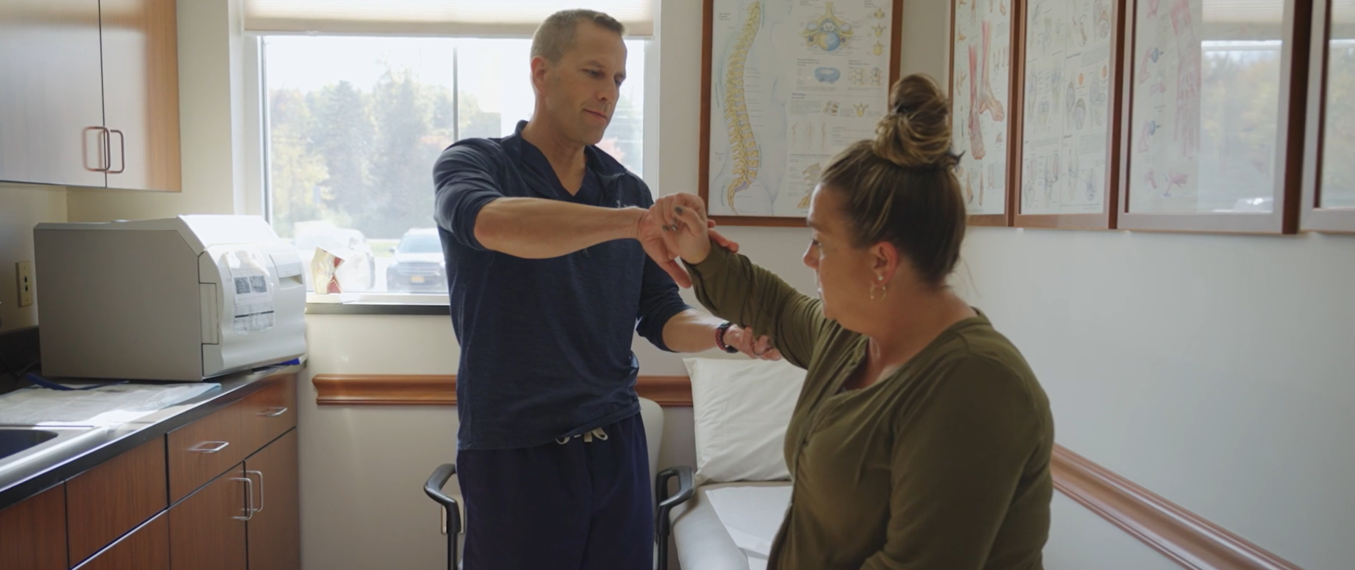 J Alan Lemley Examines Patient Elbow in Clay, NY SOS Exam Room Office