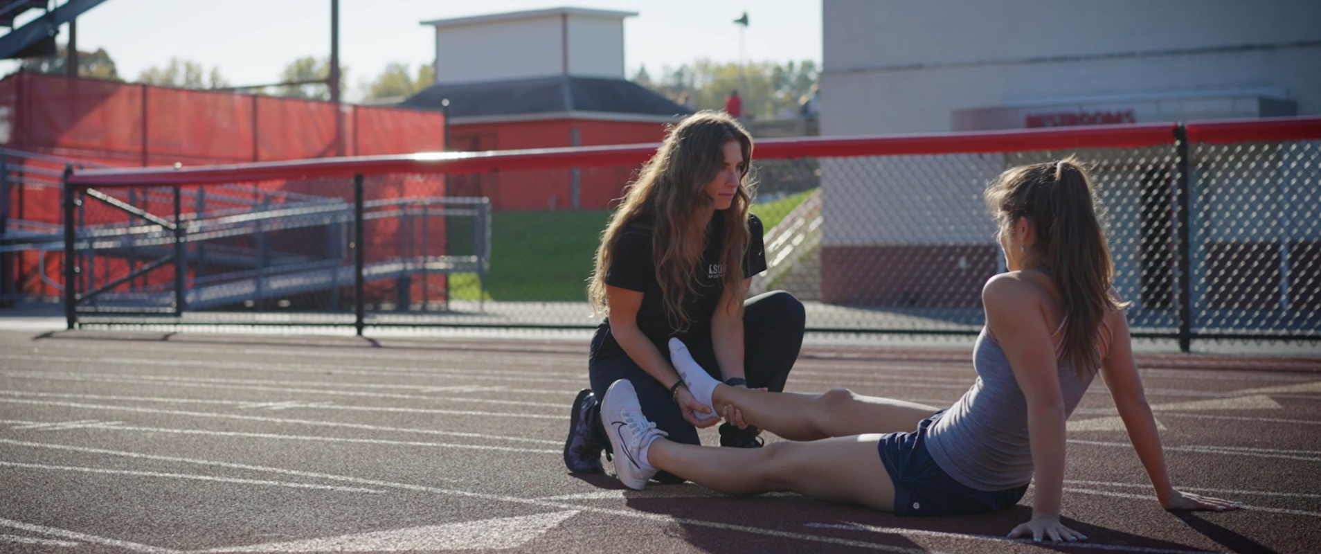 Athletic Trainer at Baldwinsville High School assesses athlete on track