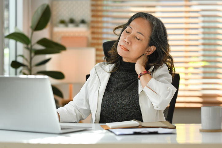 Woman sitting at desk sore neck looking at computer