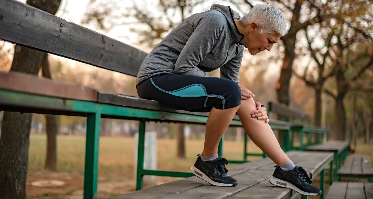 knee specialist near syracuse ny image of woman holding her knee in pain outside